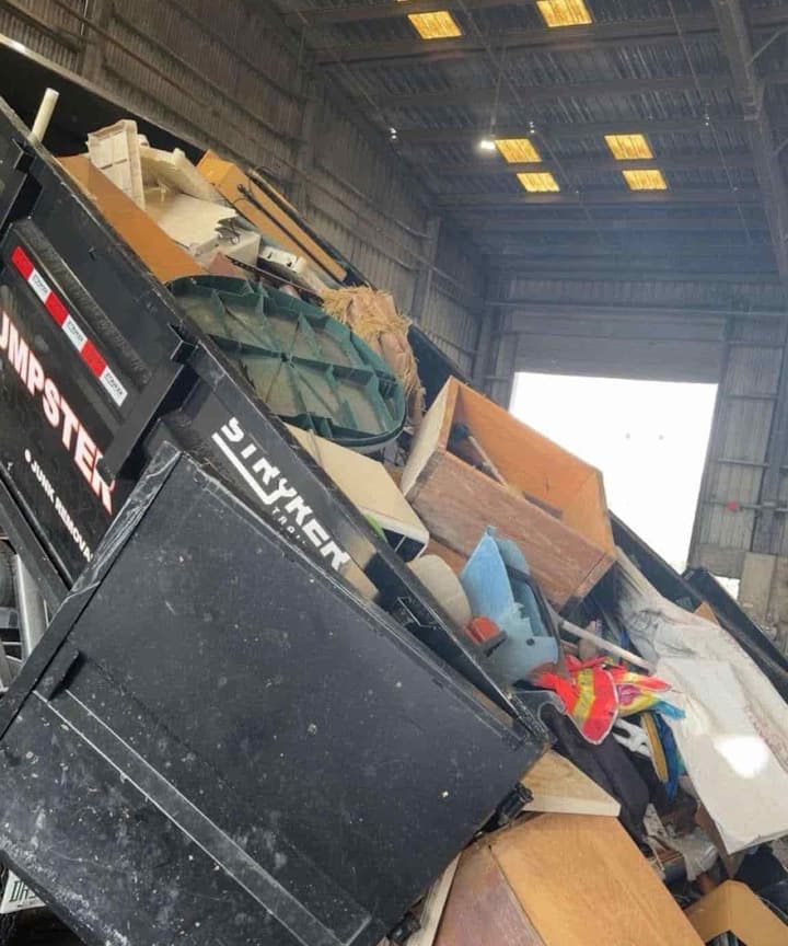 A loaded dumpster unloading furniture and other unwanted household items at a disposal facility.